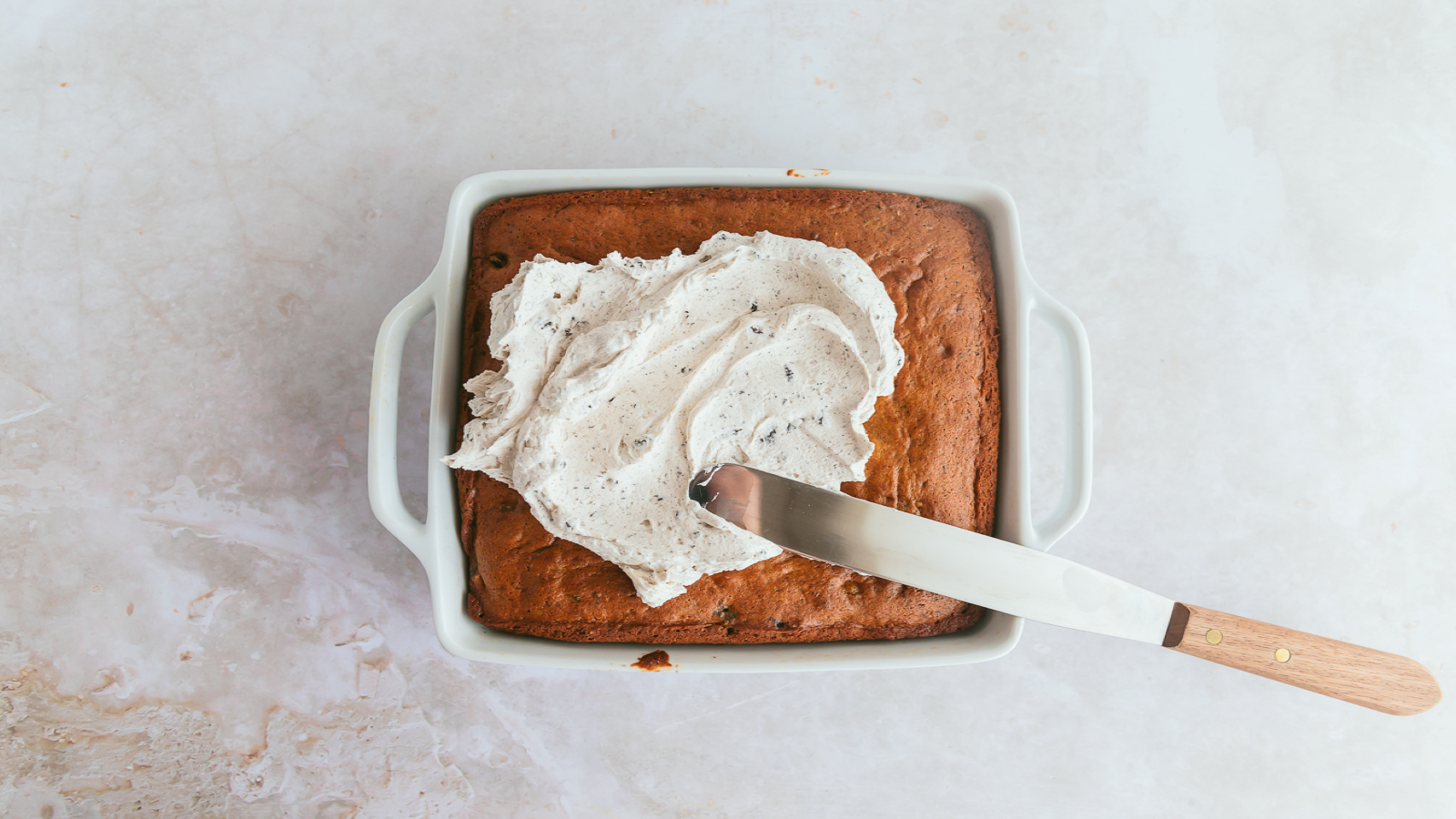 Spreading Cookies 'N Cream frozen dairy dessert on top of a cake.