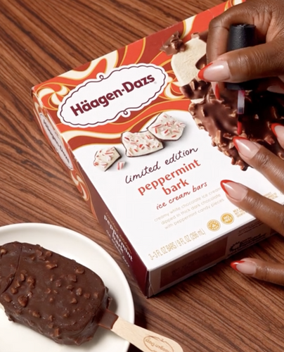A woman painting her nails while enjoying a Haagen Dazs Peppermint Bark Ice Cream Bar. 