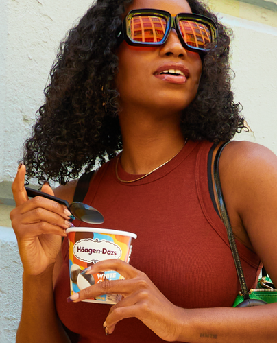 A woman in sunglasses enjoying Haagen Dazs ice cream. 