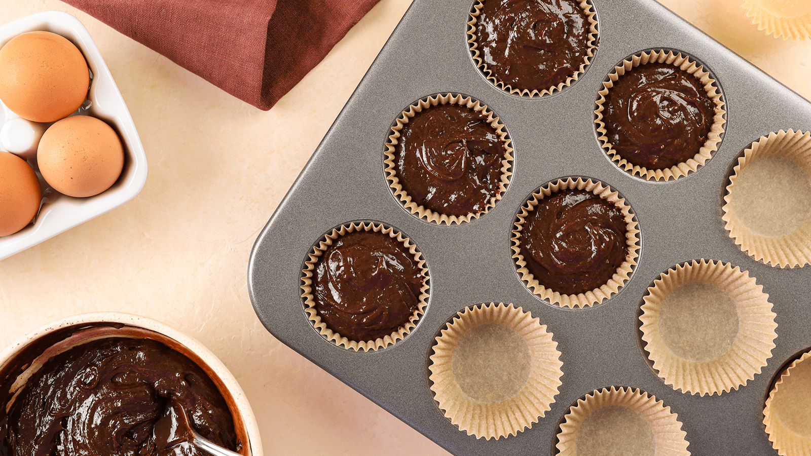 Chocolate cupcake mix on a cupcake tray on a counter top.