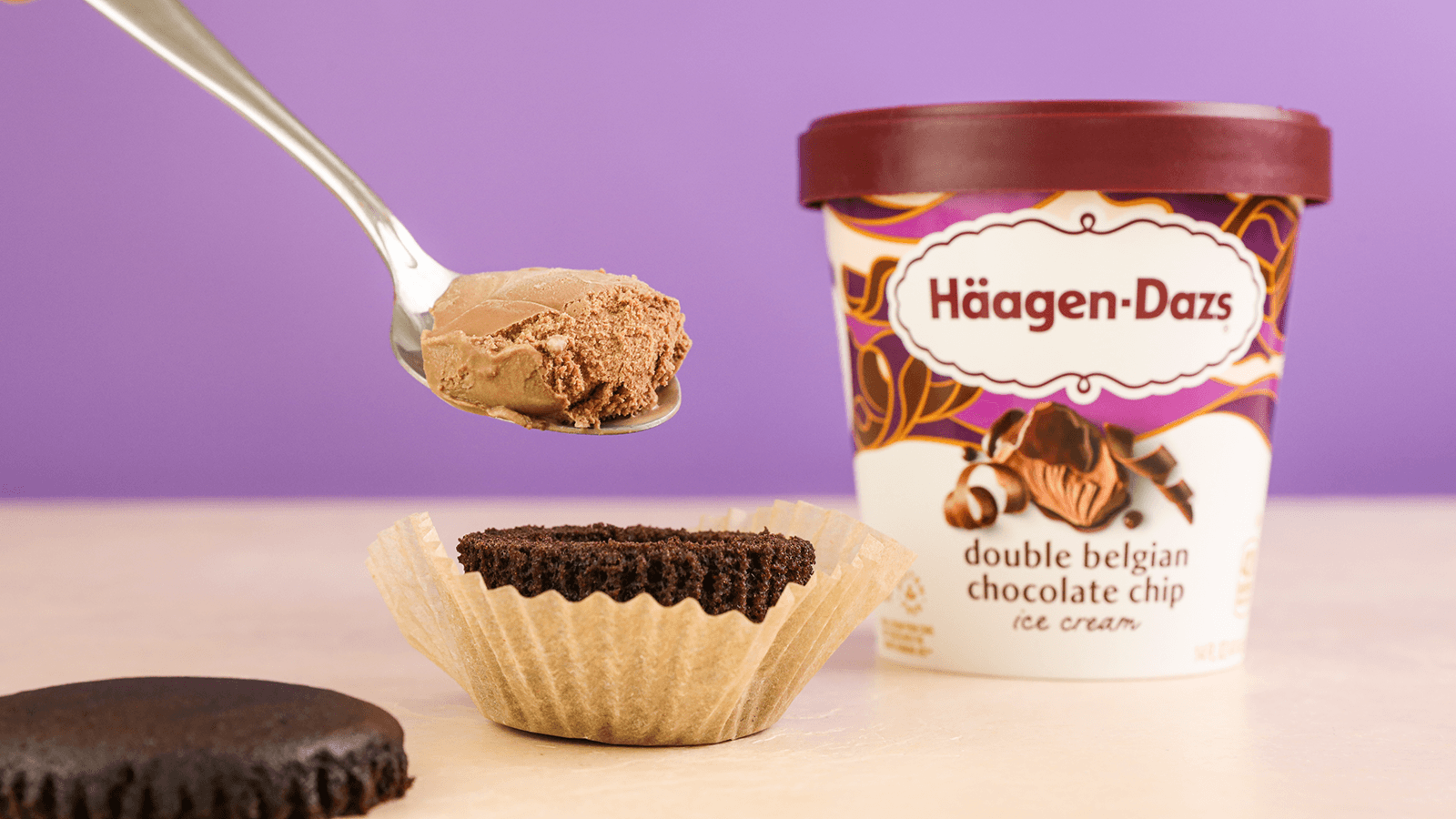 Haagen Dazs Double Belgian Chocolate Chip ice cream on a spoon being placed on a cupcake.