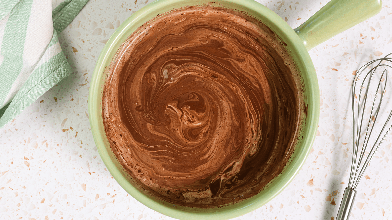 Chocolate glaze in a green bowl after being whisked.