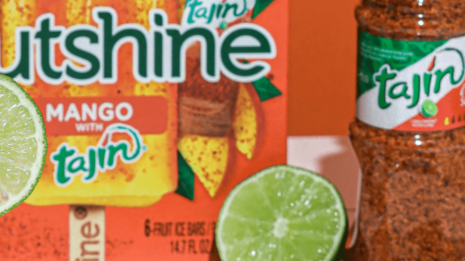 Close up of Outshine Mango Tajin Frozen Fruit Bars next to a lime and a bottle of tajin.