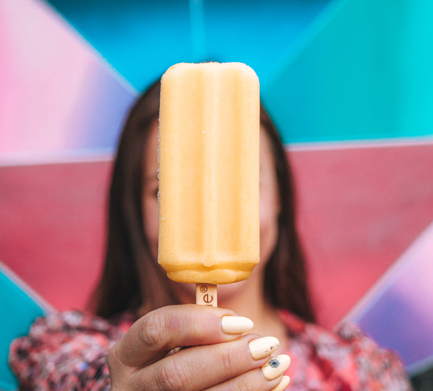 Closeup of a woman holding an Outshine Frozen Fruit Bar. 